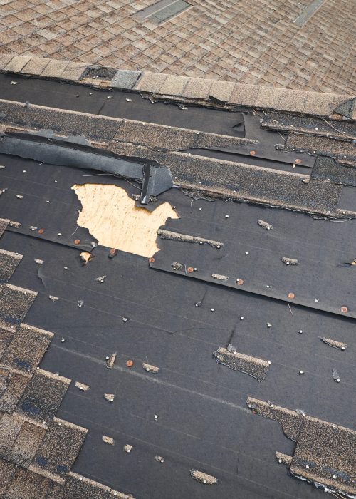 Damaged house roof with missing shingles after hurricane Ian in Florida. Consequences of natural disaster.