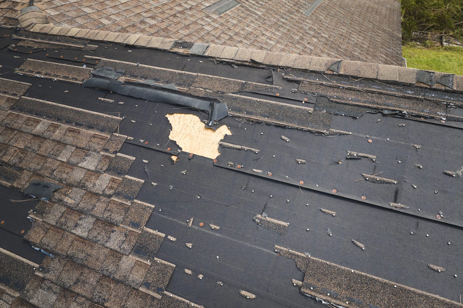 Damaged house roof with missing shingles after hurricane Ian in Florida. Consequences of natural disaster.